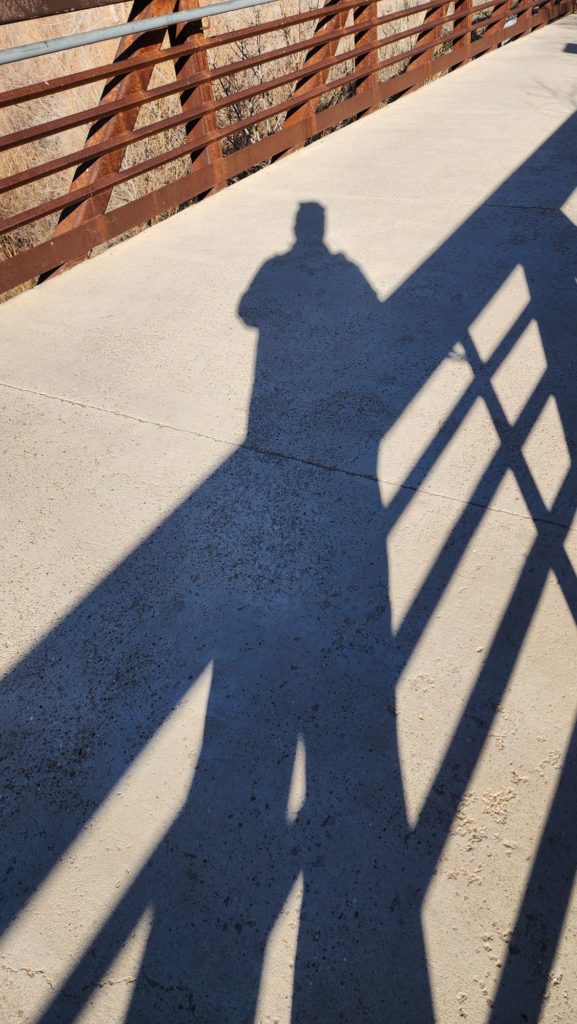 Color photo of shadows. Humanoid and bridge shadows. Light and shadow. Bridge structure. 